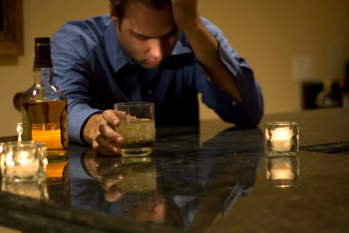 Мужчина с бутылкой и бокалом алкоголя